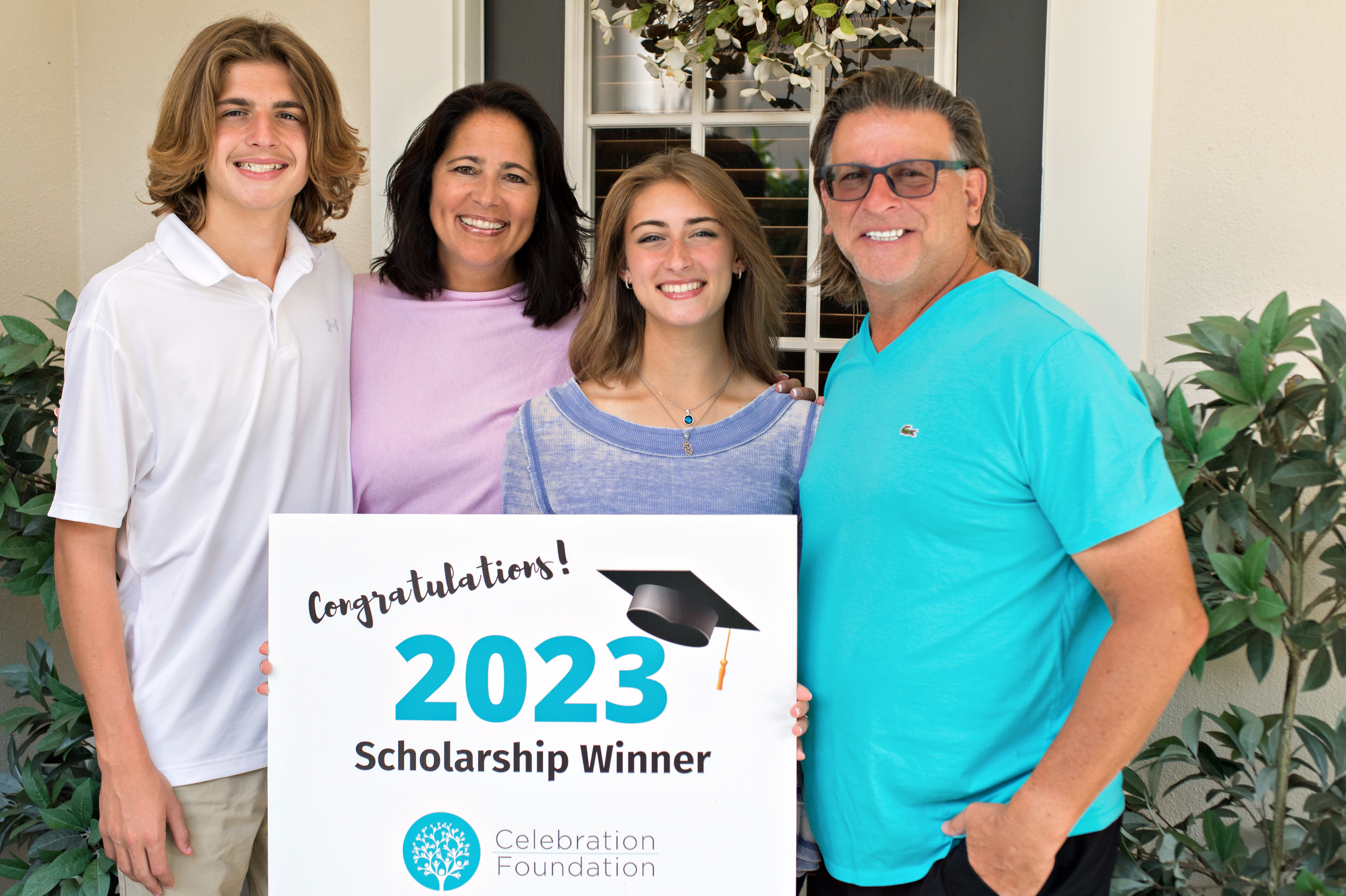 Family standing outside with scholarship winner sign